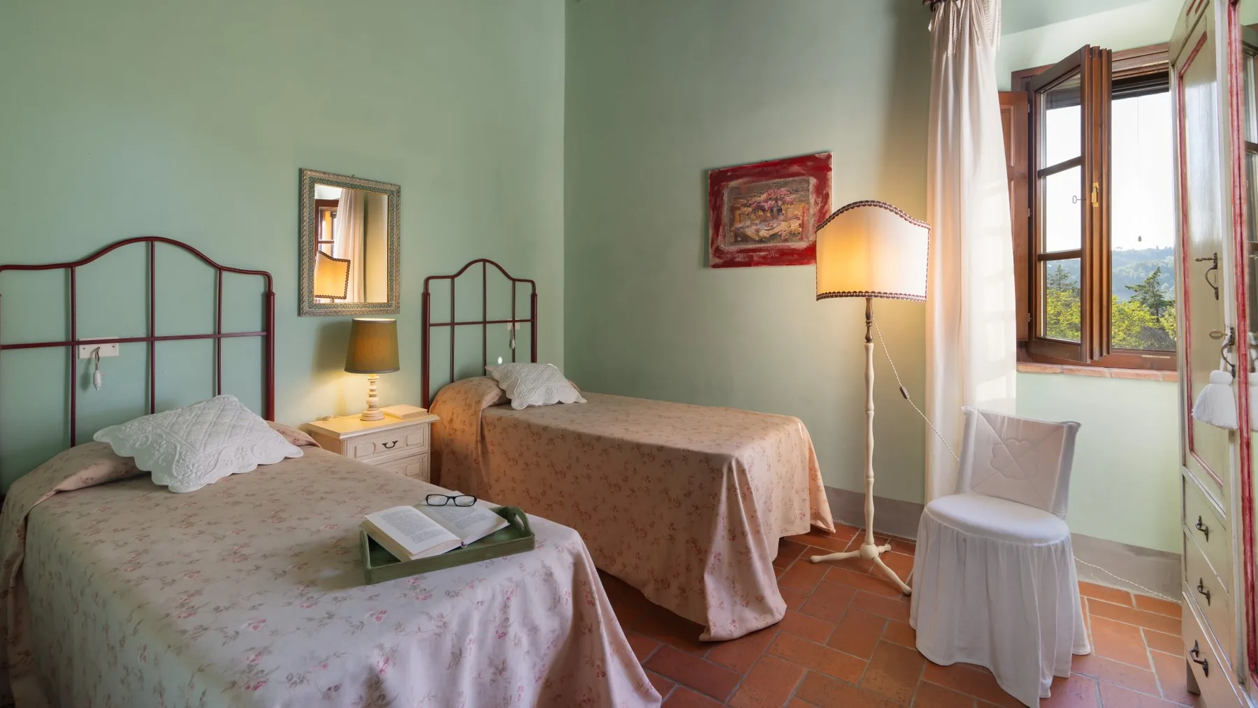 Un dormitorio con dos camas, mesitas de noche y una ventana abierta.