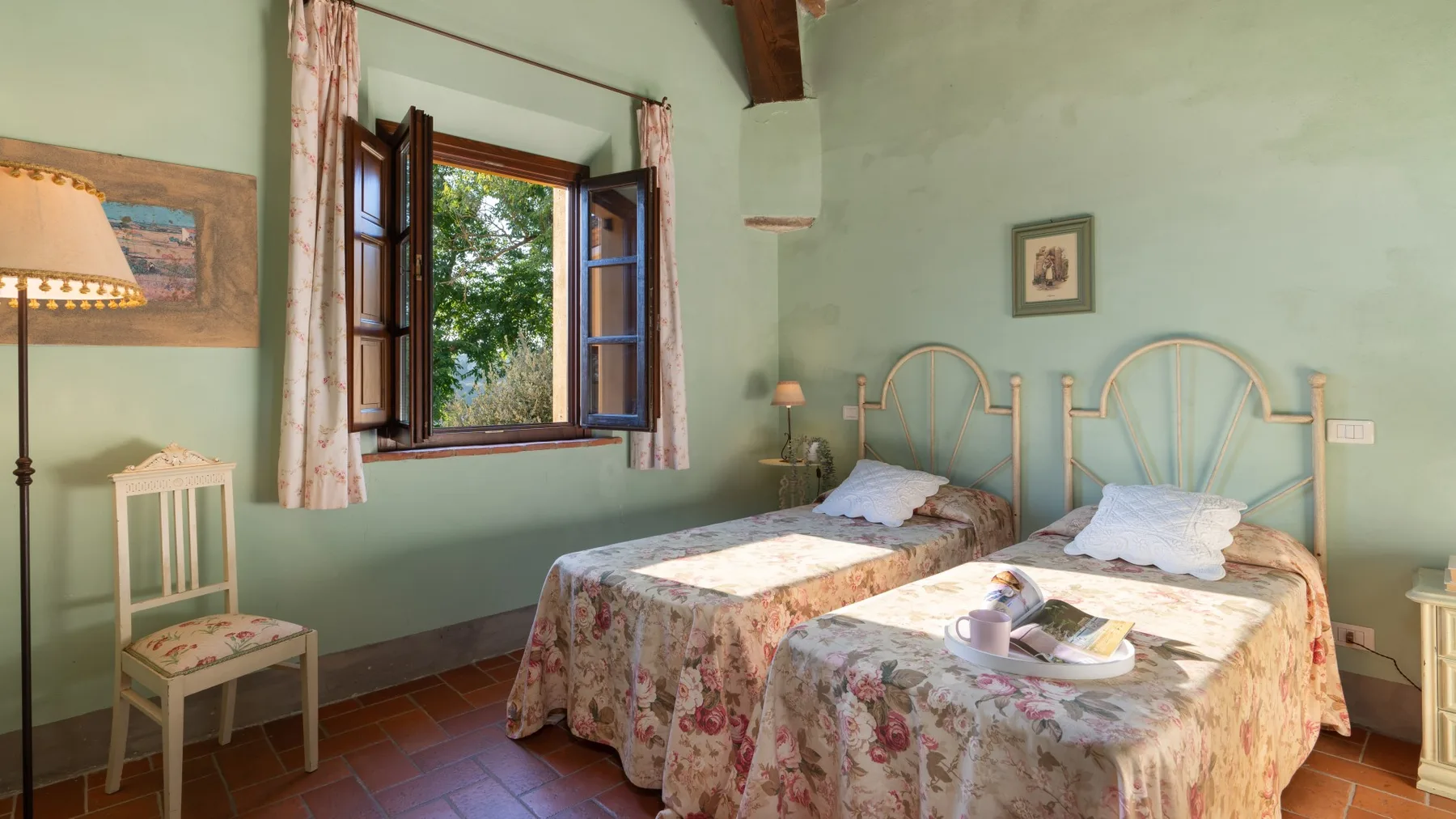 Un dormitorio con dos camas bajo una ventana abierta.