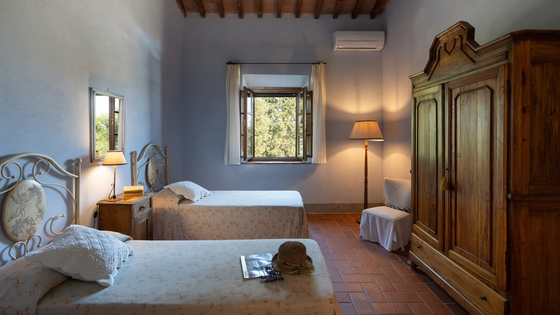 Un dormitorio con dos camas, un gran armario de madera y ventanas con vistas a vegetación.