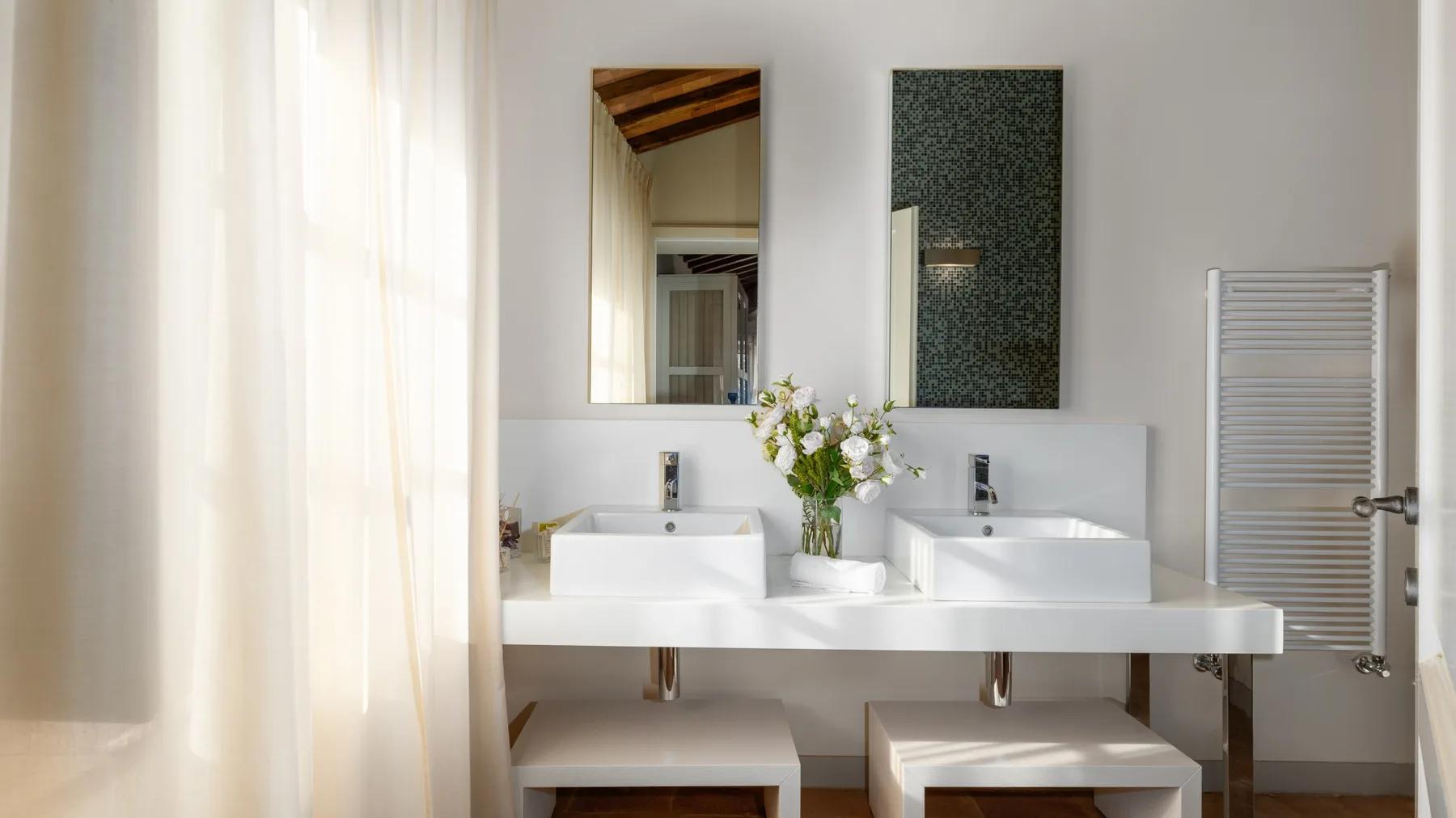 Un tocador de baño con dos lavabos, espejos y una cortina translúcida.