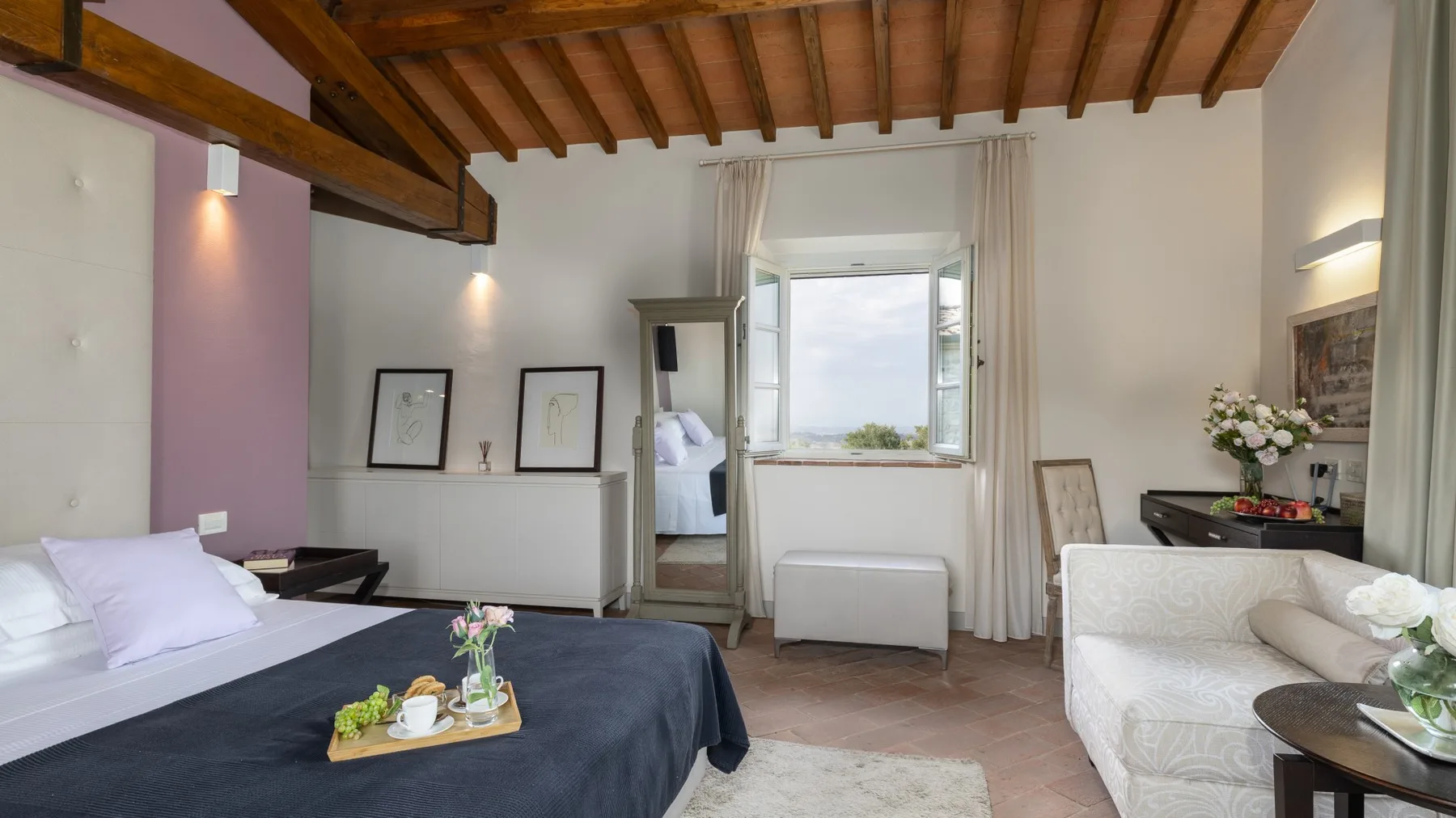 Un dormitorio con una cama, una zona de estar y una ventana con vistas al agua.