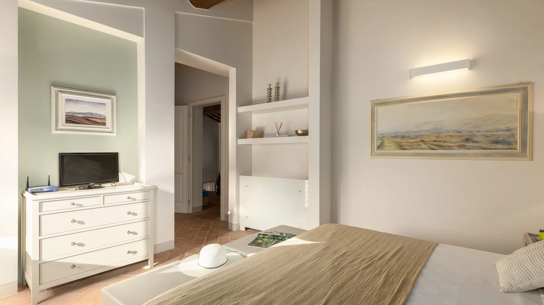 Un dormitorio con una cama, una cómoda y cuadros en las paredes.