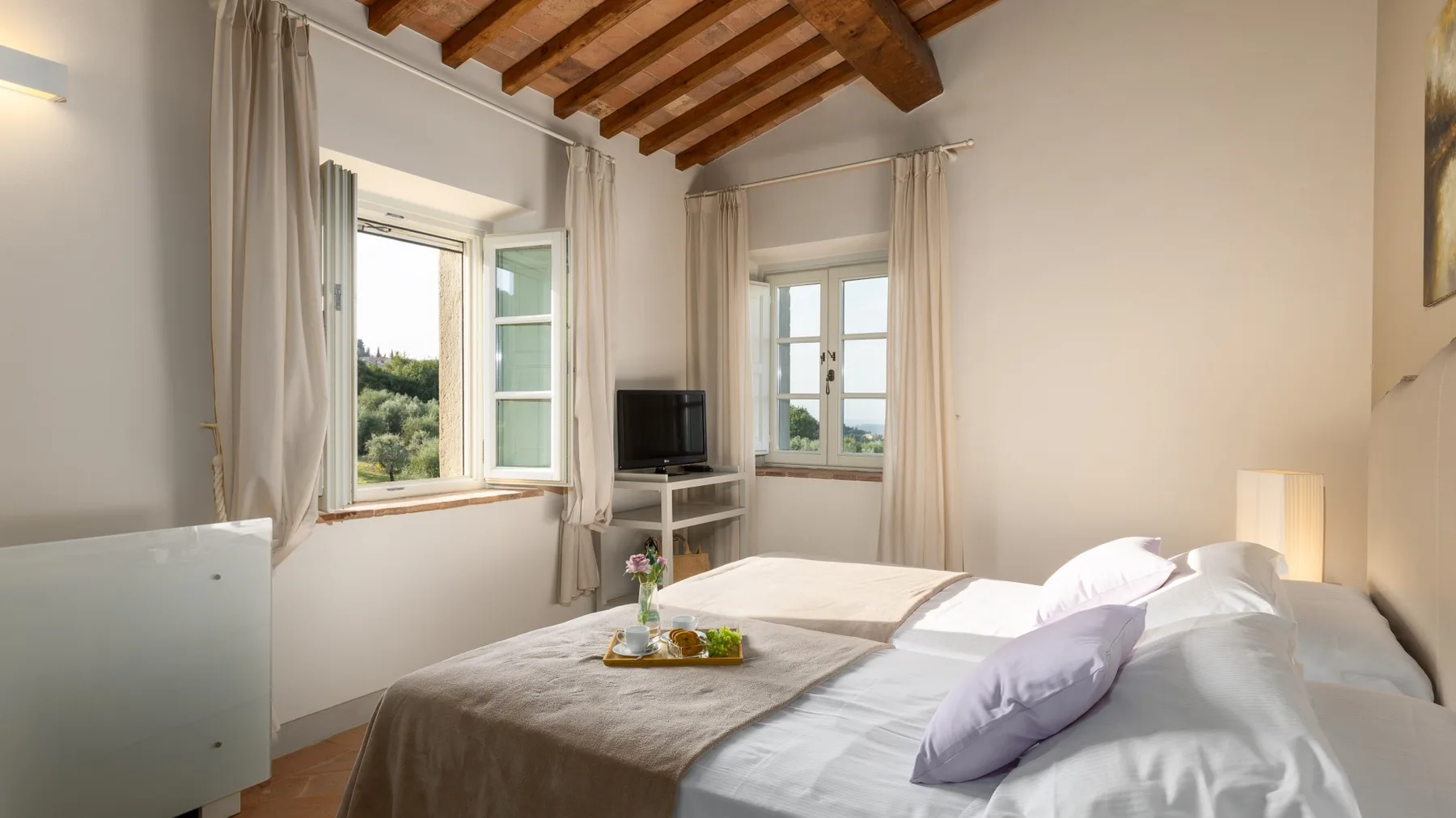 Un dormitorio luminoso con una cama bajo vigas de madera a la vista.