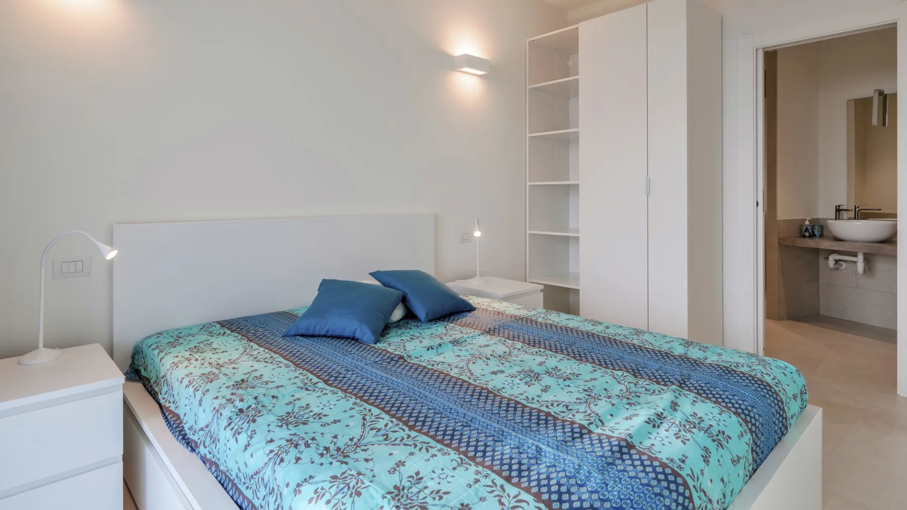 Un dormitorio con una cama cubierta con una colcha azul estampada.