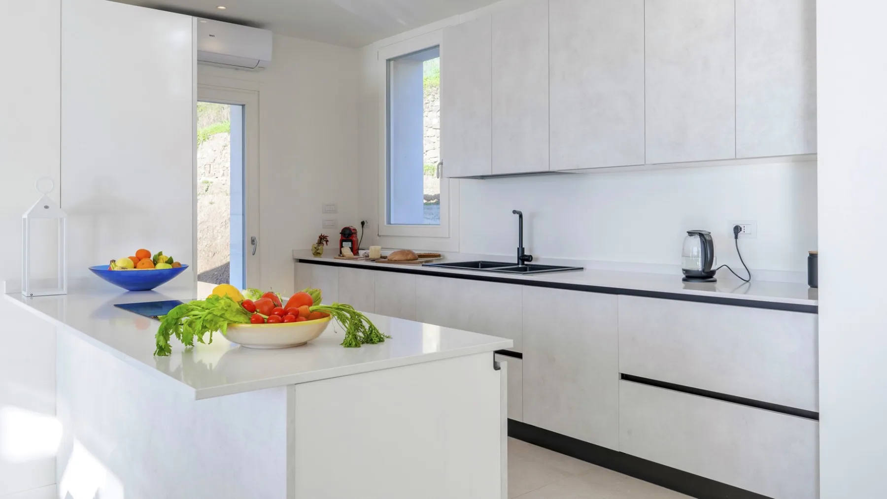 Una cocina moderna y luminosa con armarios blancos e isla central.