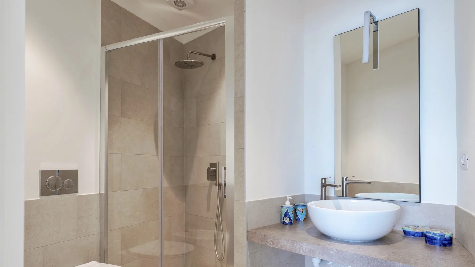 Un baño con una ducha de vidrio y un lavabo bajo un espejo.