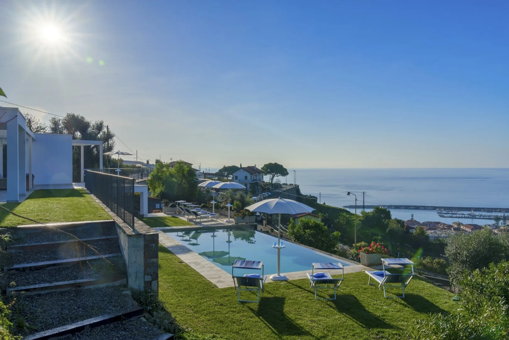 Una piscina exterior y una zona de asientos miran al océano bajo un cielo despejado.