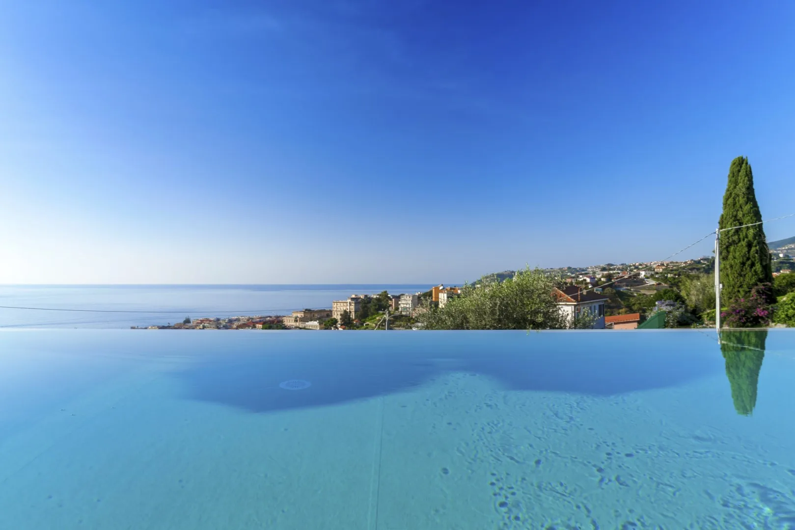 Una piscina infinita da al mar y a una ladera costera.