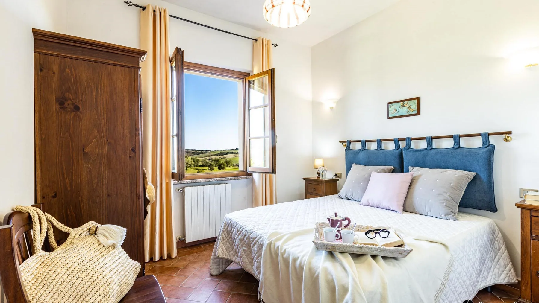 A bright bedroom with a bed beside an open window.