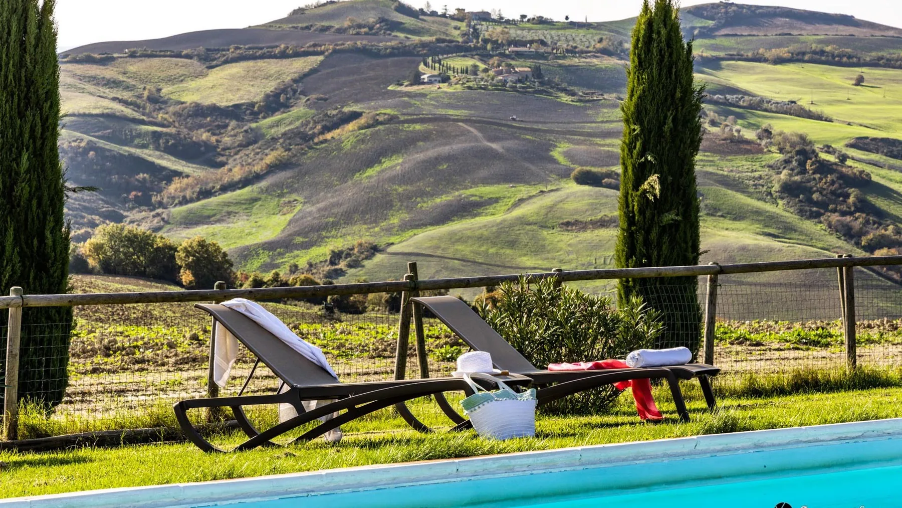 Outdoor poolside seating overlooks rolling green hills.