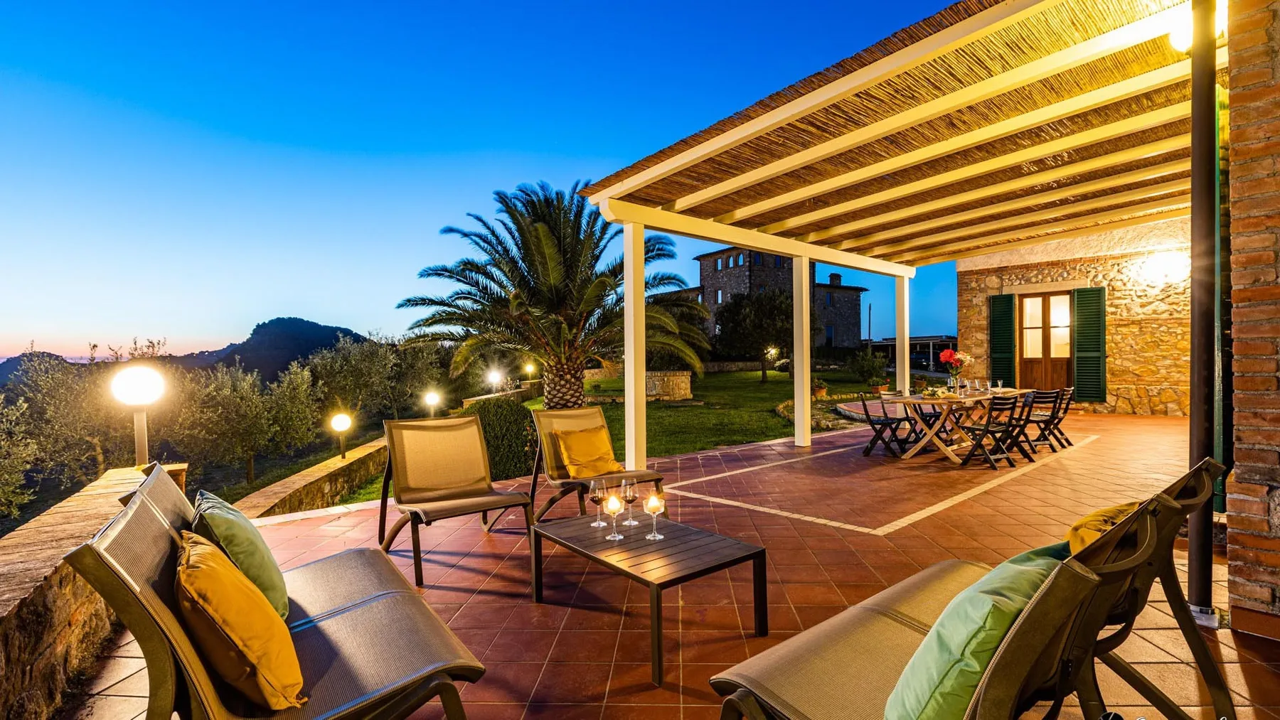 An outdoor patio with seating and a table beneath a covered pergola.