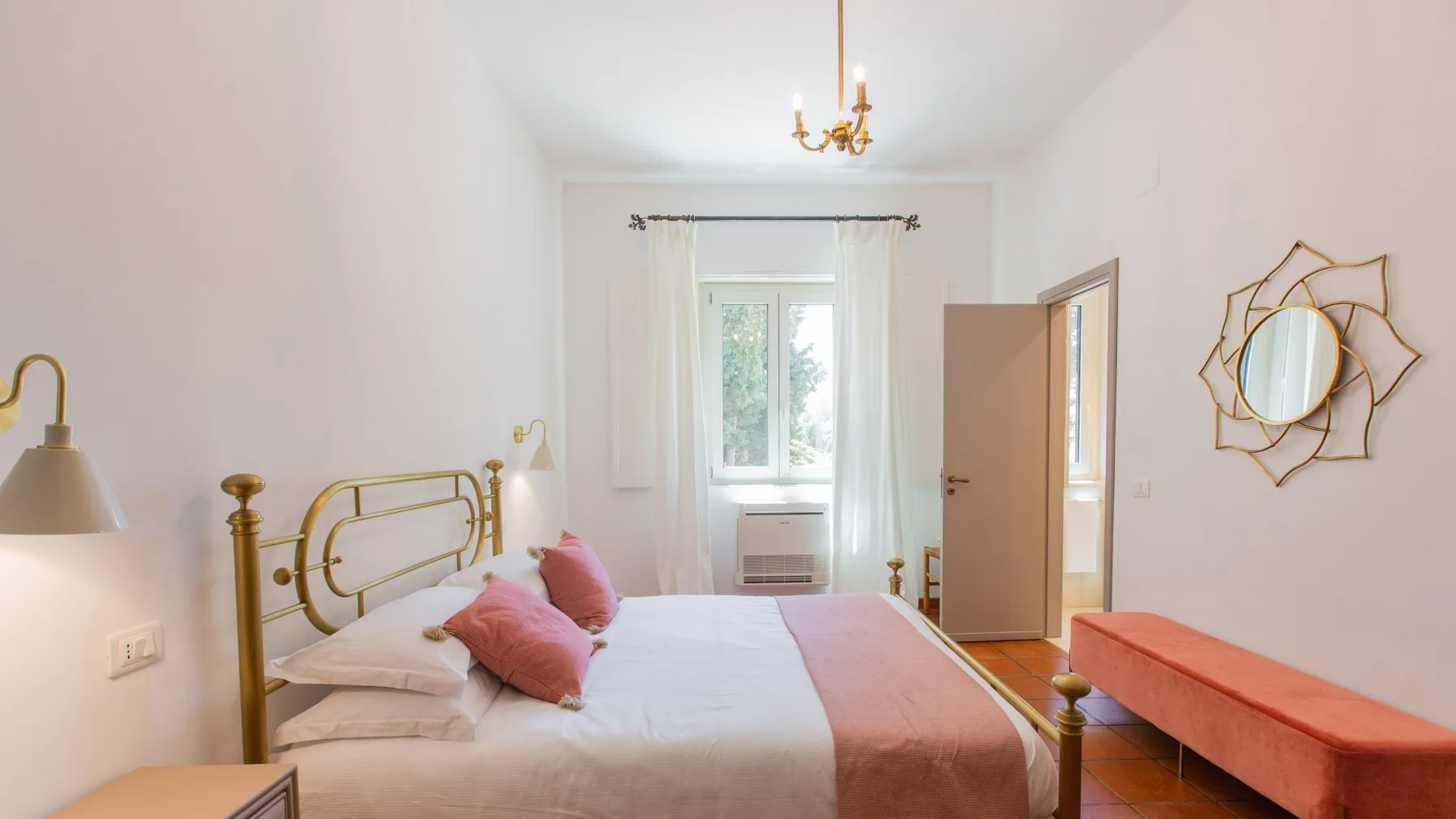 Un dormitorio luminoso con una cama hecha y una ventana al fondo.