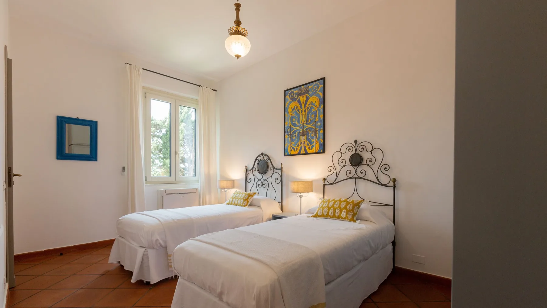 Un dormitorio con dos camas, cabeceros de metal oscuro y una ventana.