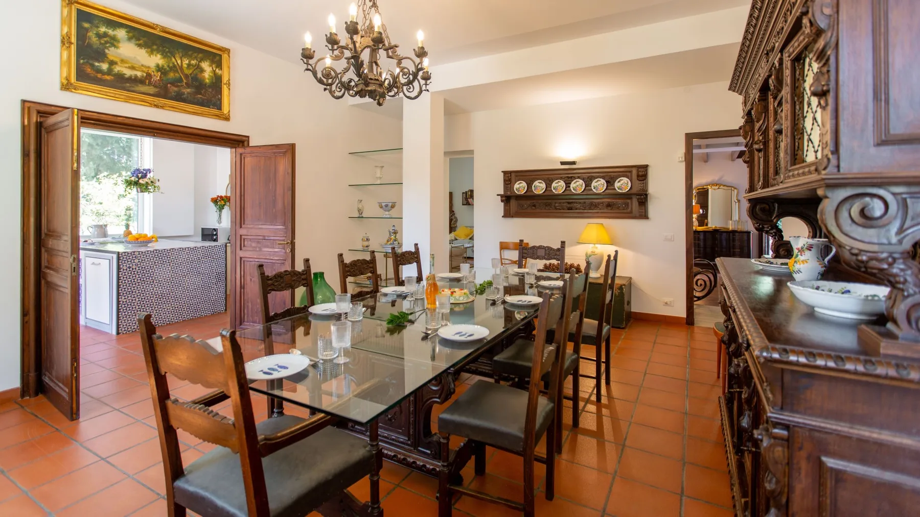 Comedor con una mesa de cristal, sillas de madera y un gran mueble tallado.