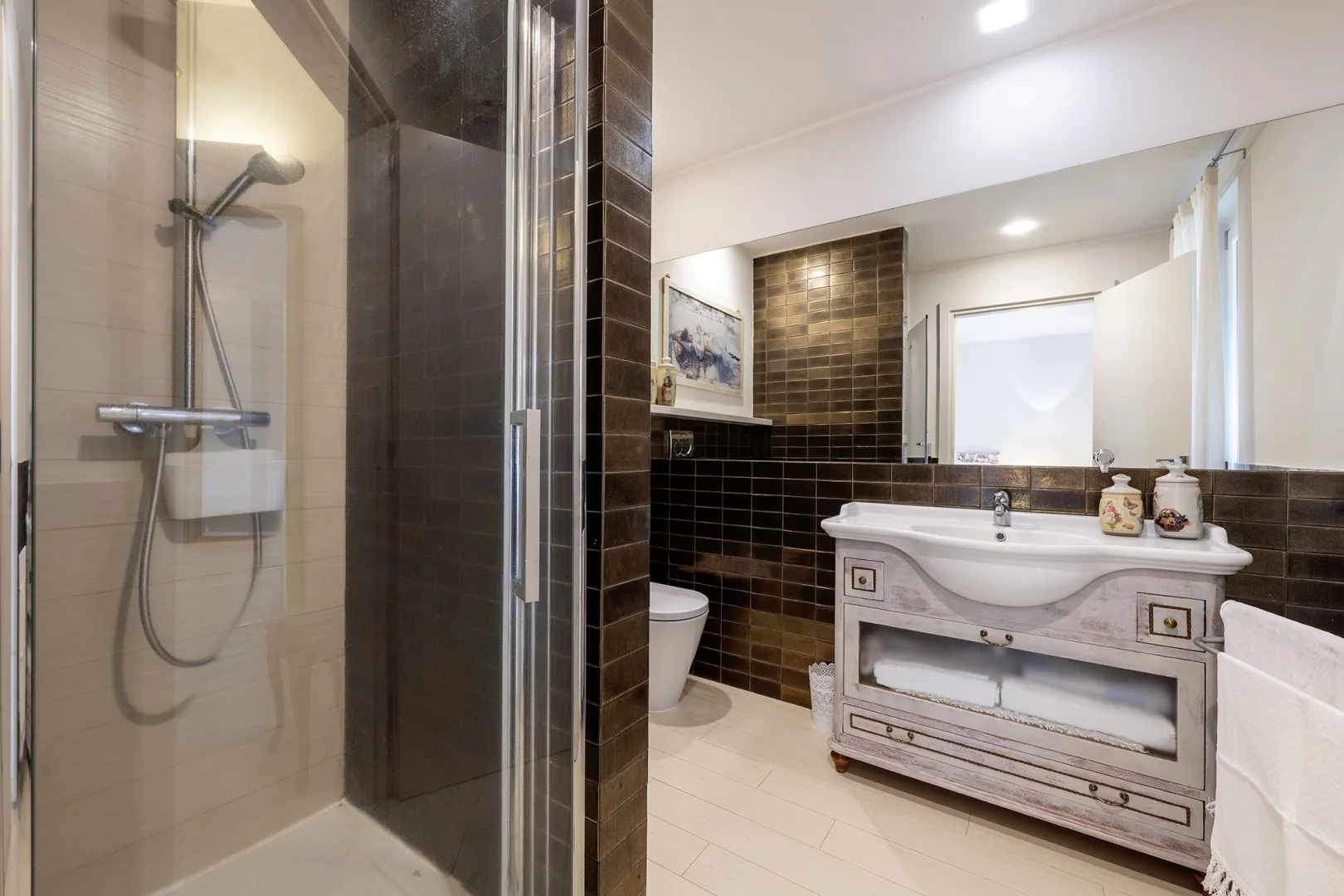A bathroom with a glass shower and a vanity beside the sink.