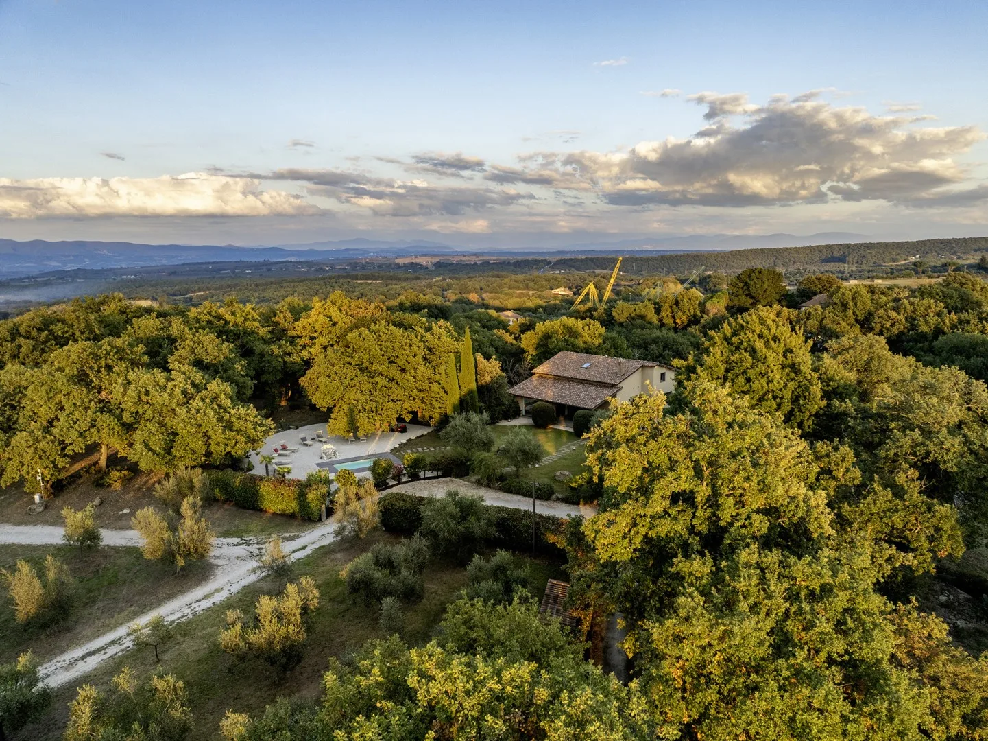 A small building sits among dense trees, with rolling hills stretching across the horizon.