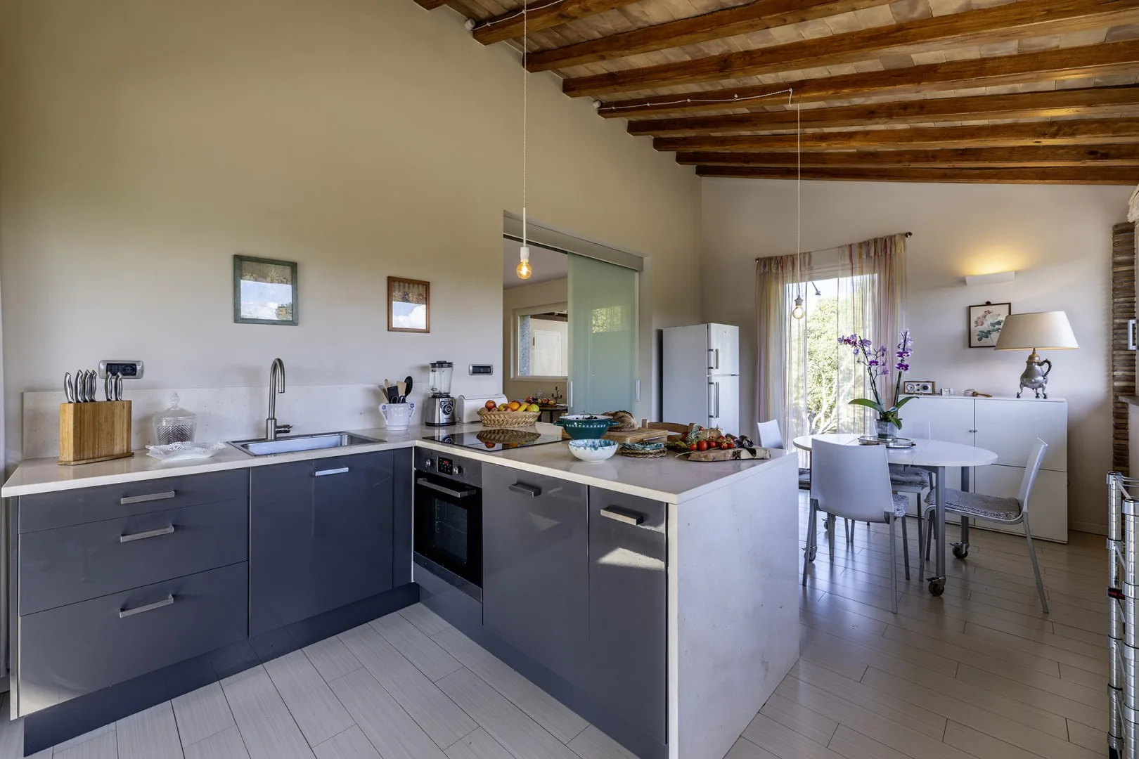 A modern kitchen opens onto a dining area with a table and chairs.