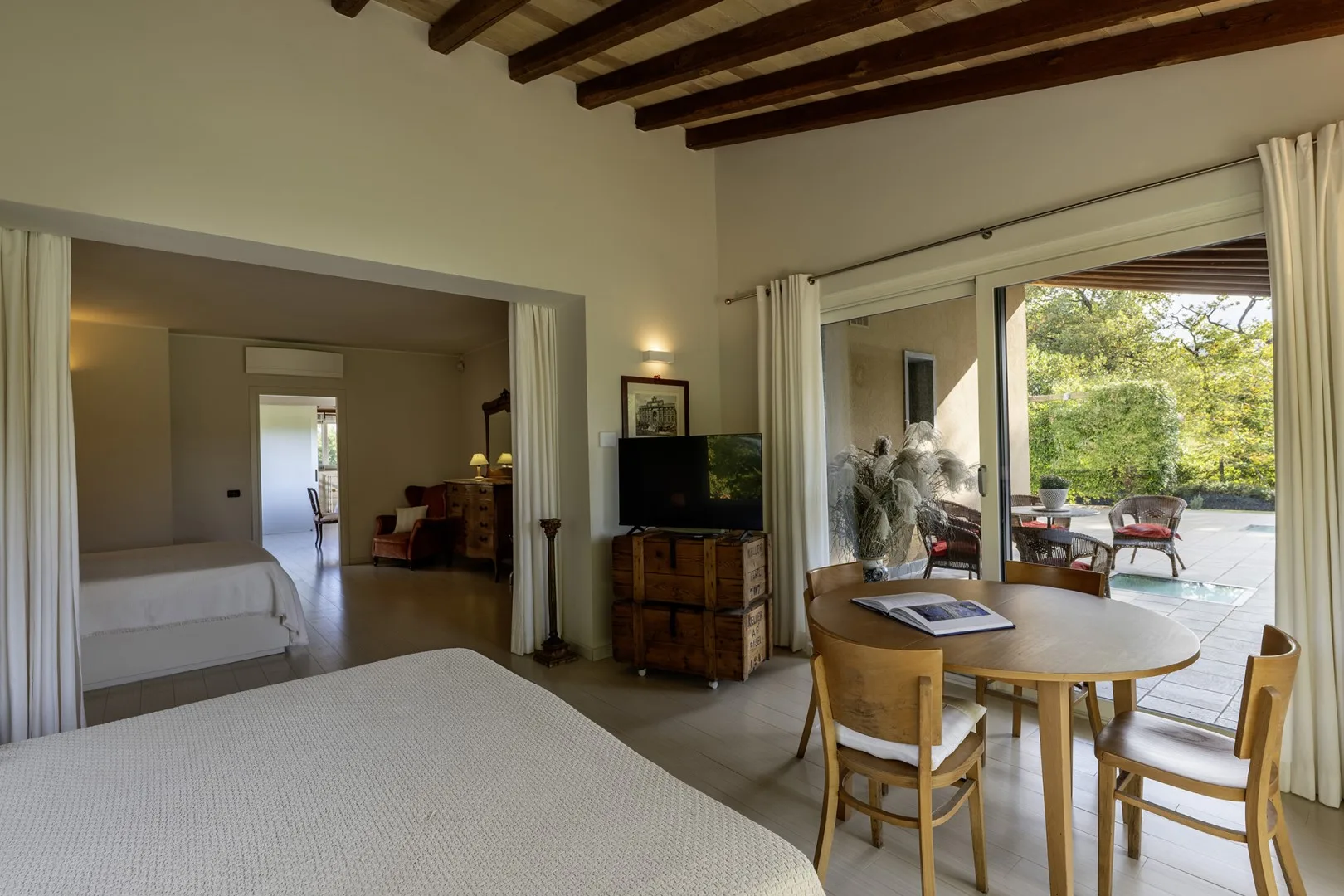 A bright bedroom and sitting area open onto a patio through sliding glass doors.