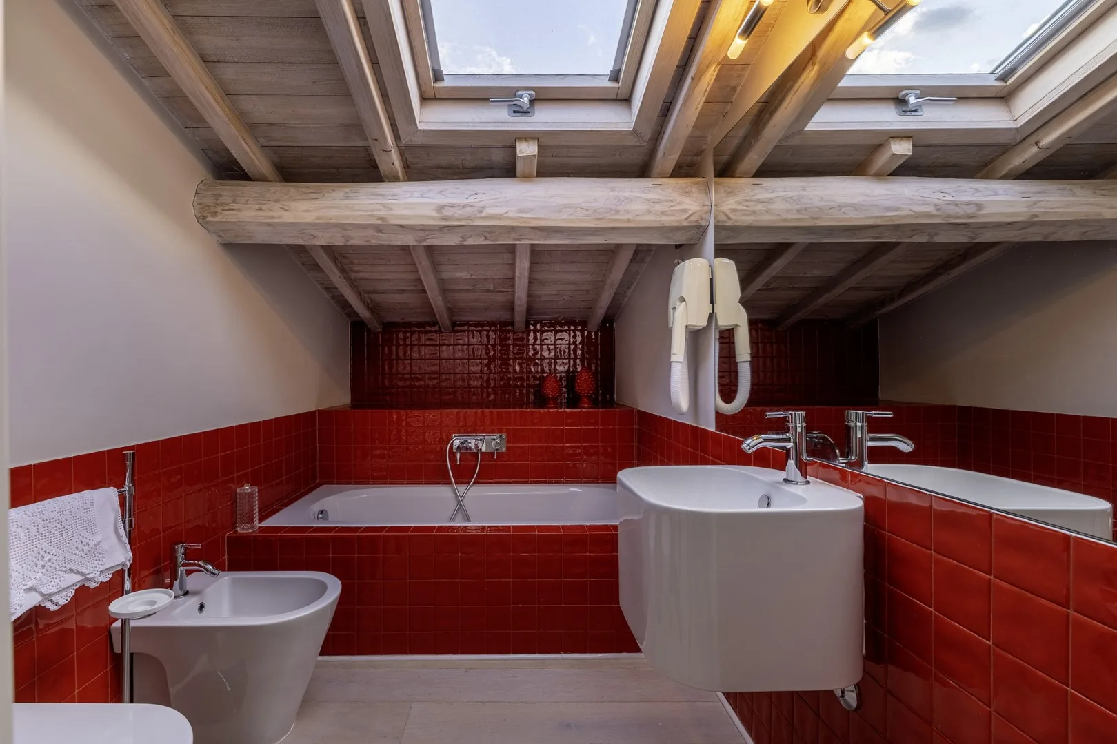 A bathroom with a bathtub and sink beneath skylights.