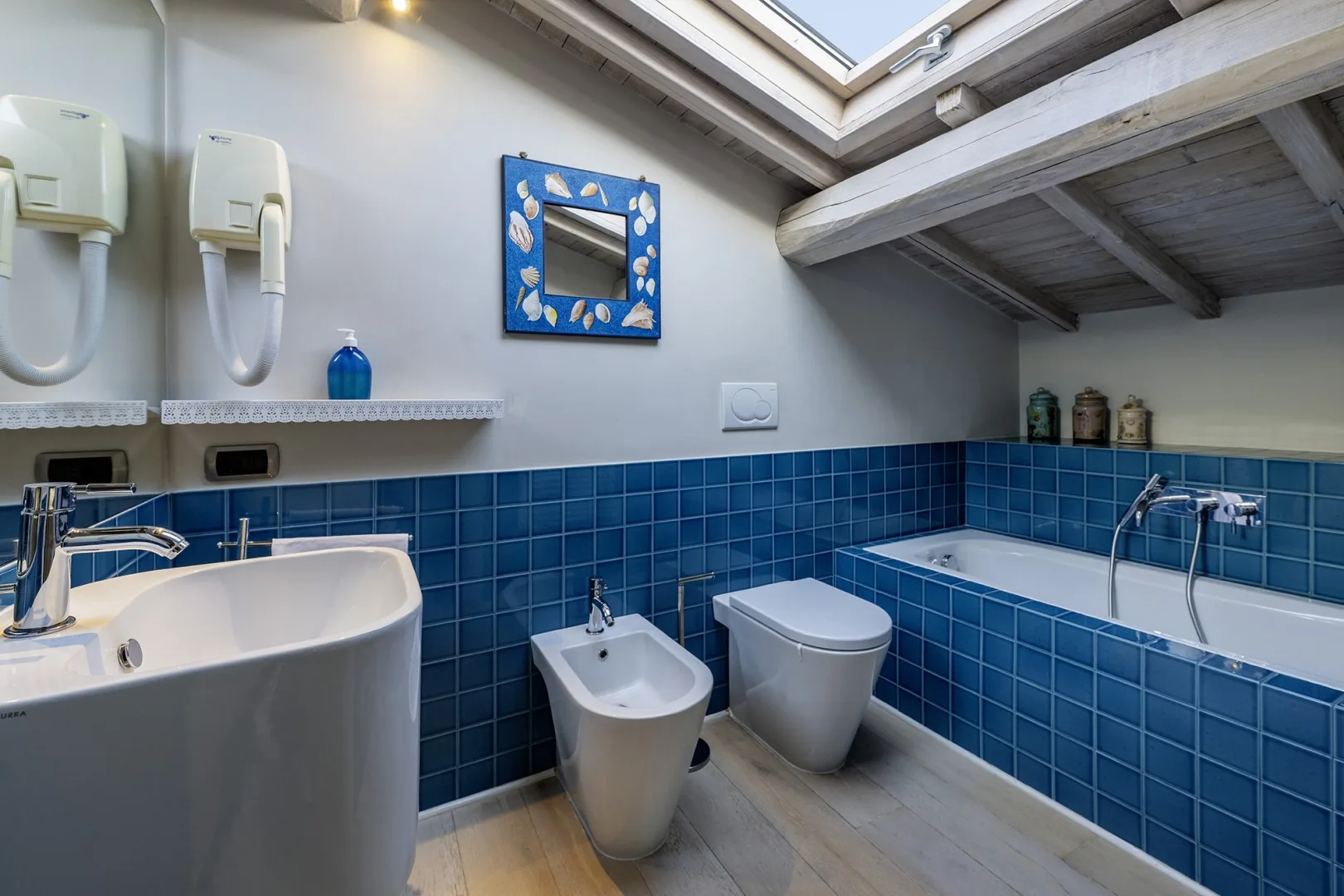 A bathroom with a bathtub, sink, and skylight.