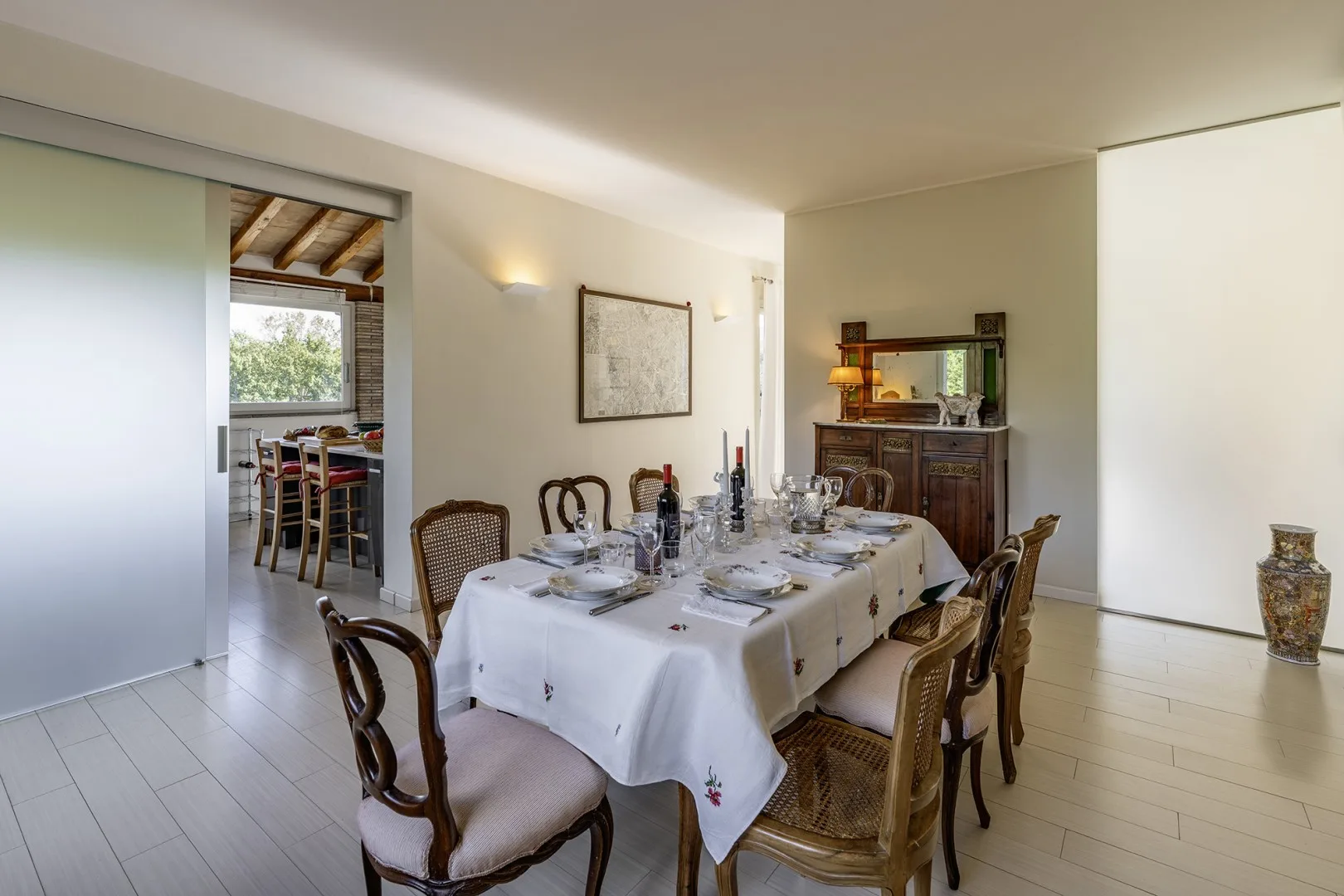A dining room with a long table set for a meal and a wooden sideboard.
