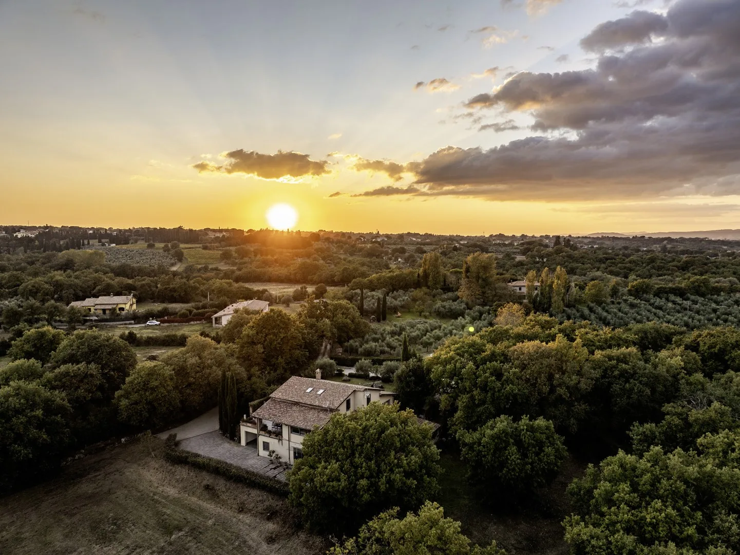 A sunset over a wooded countryside dotted with homes.