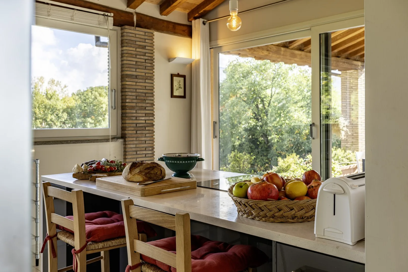 A bright dining area with a table beside large windows overlooking greenery.