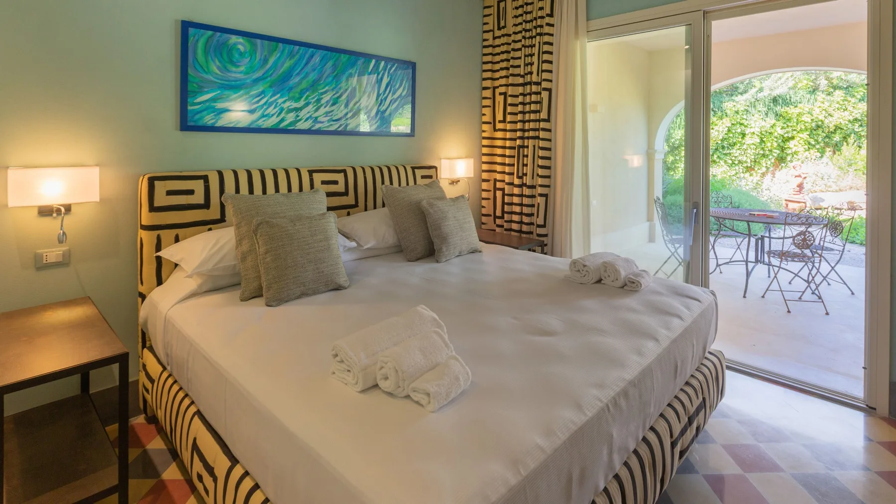 A bedroom with a large bed and glass doors opening onto a patio.