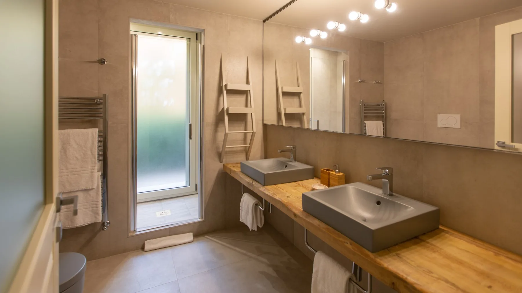 A bathroom with two vessel sinks set along a long wooden vanity.