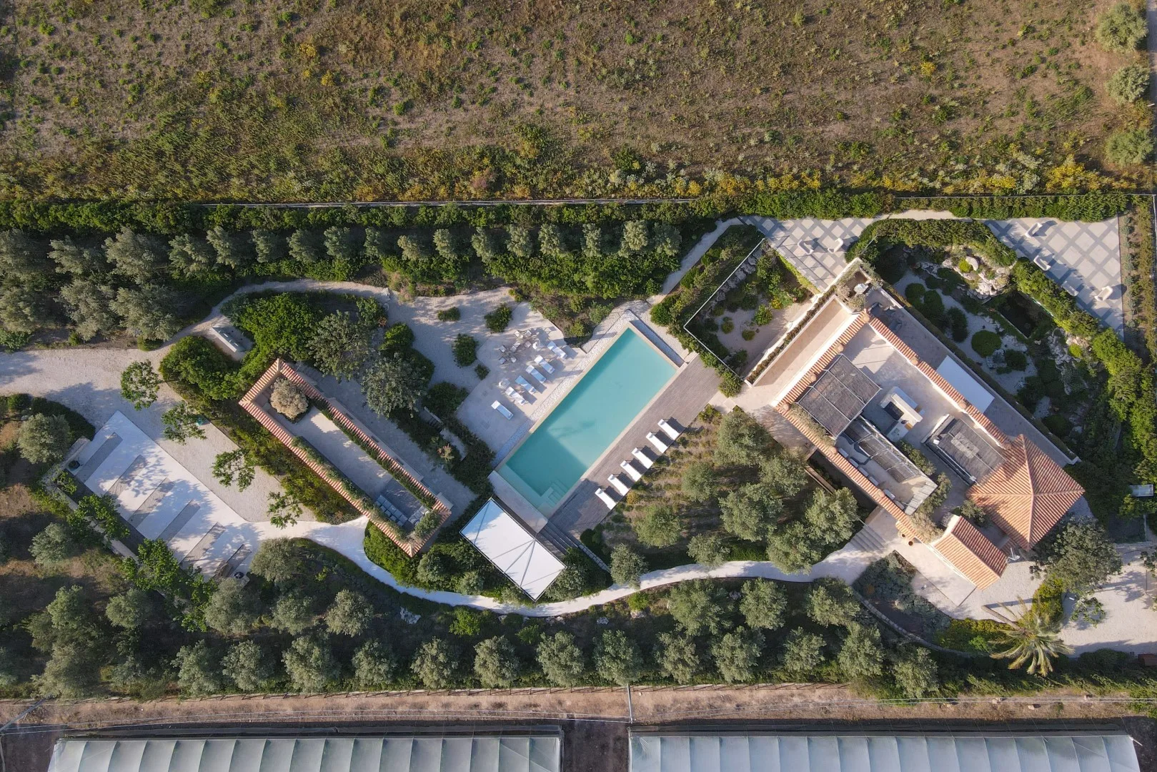 An aerial view of a landscaped property with a swimming pool and surrounding buildings.