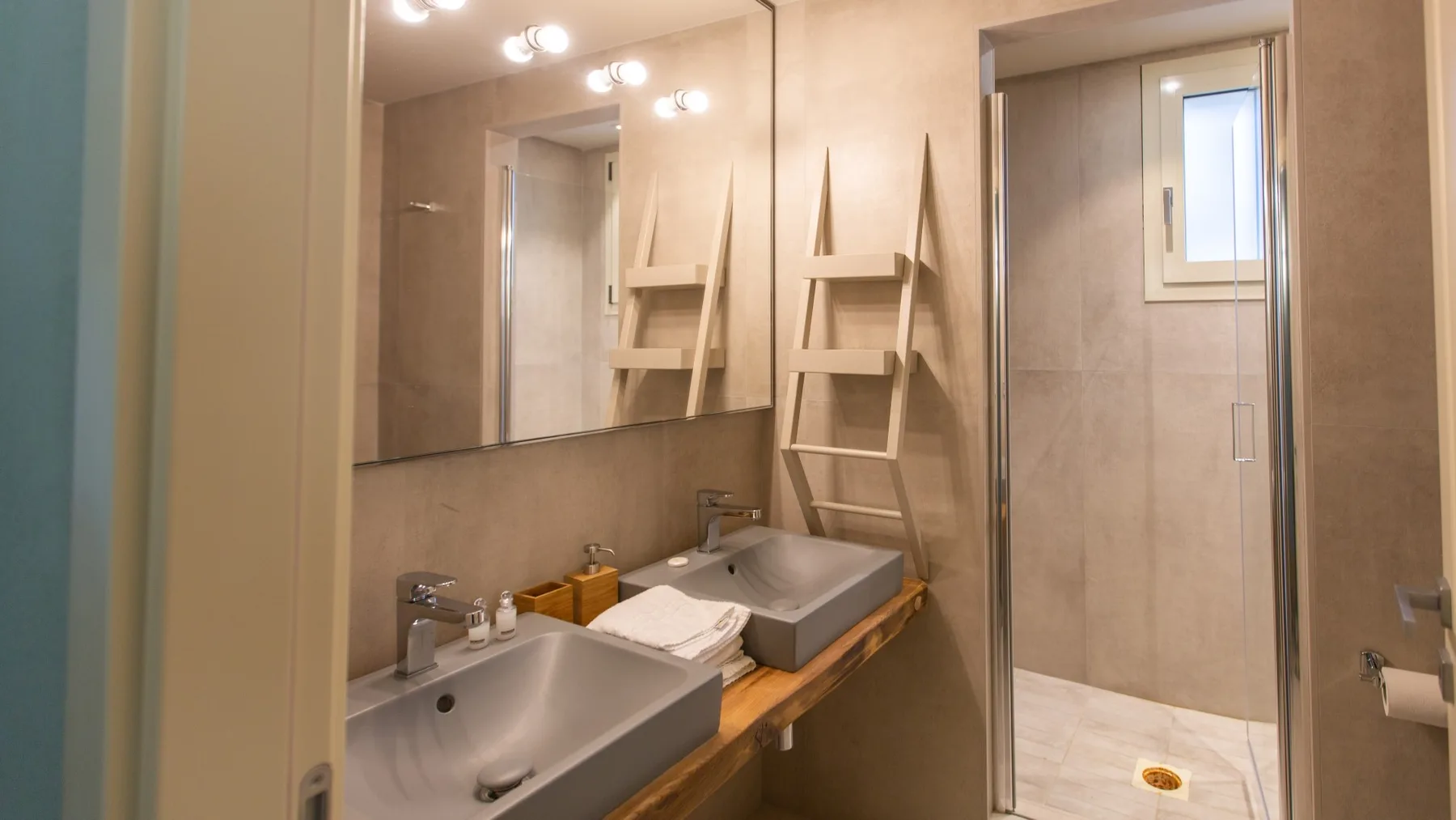 A bathroom with two sinks, a large mirror, and a walk-in shower.