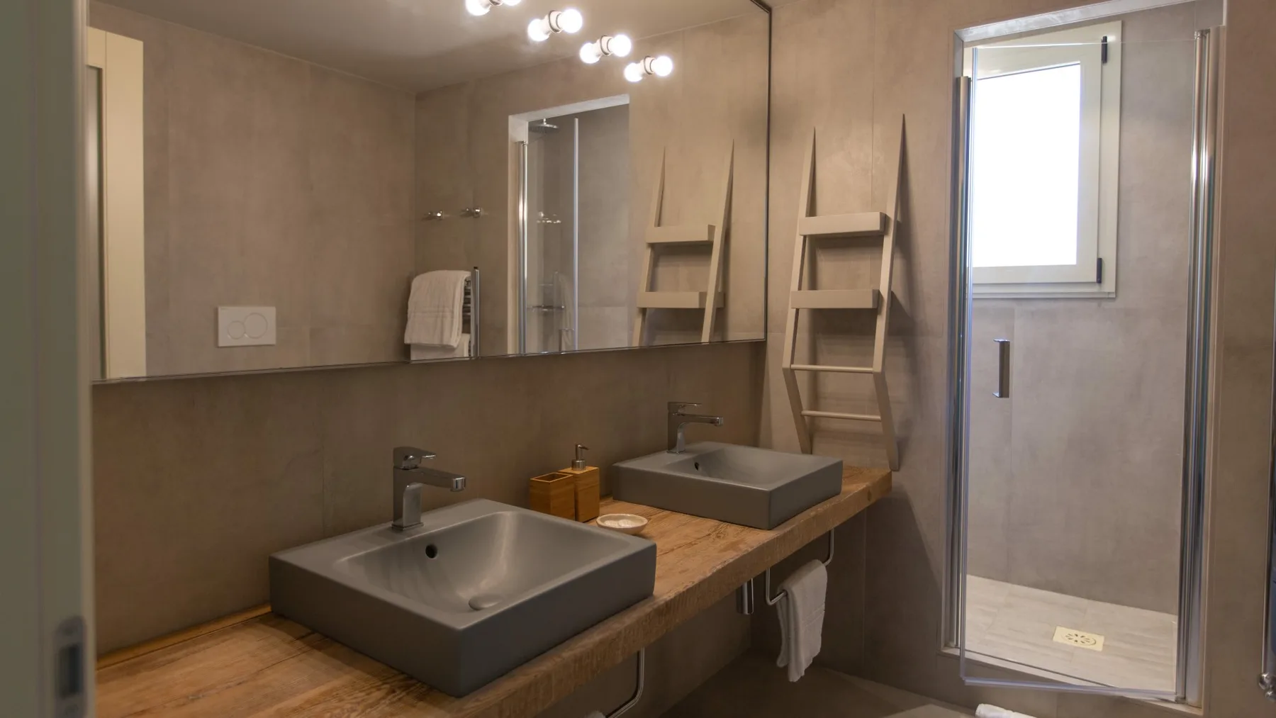 A bathroom vanity with two basins, a large mirror, and a shower.