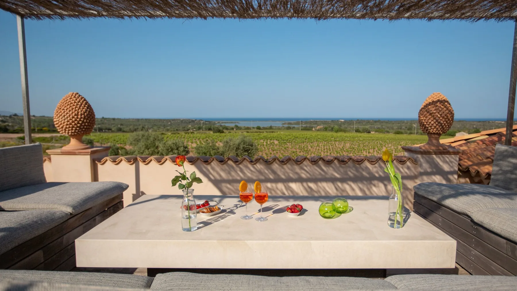 A rooftop terrace overlooks green coastal vegetation and the sea.