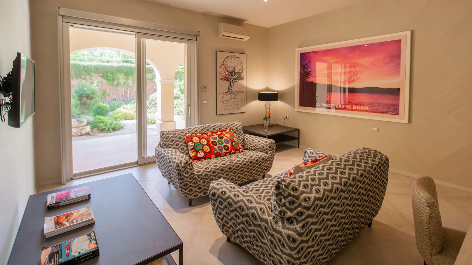 A living room with patterned seating, a coffee table, and sliding glass doors.