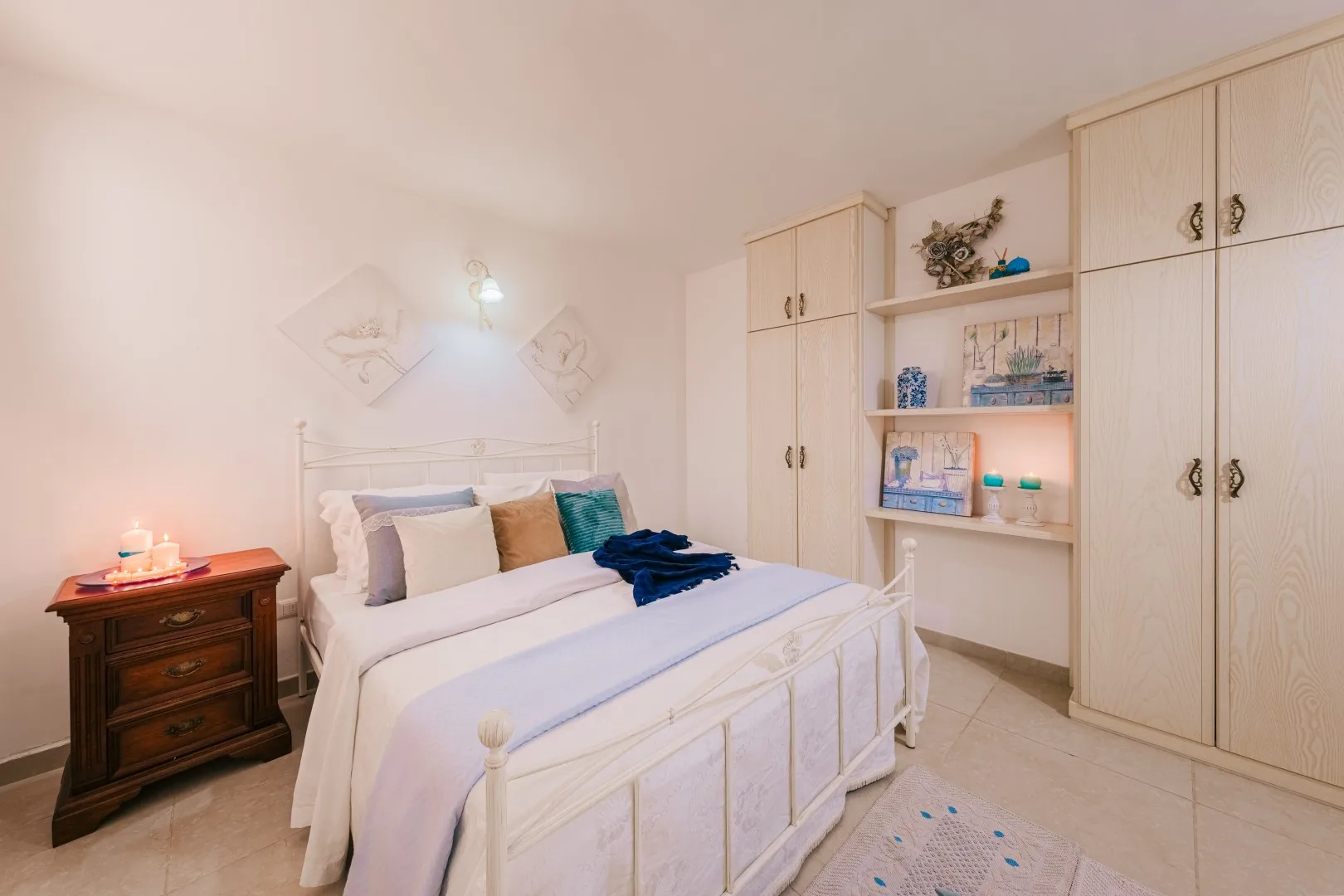 Un dormitorio con una cama blanca junto a armarios empotrados y estantes abiertos.