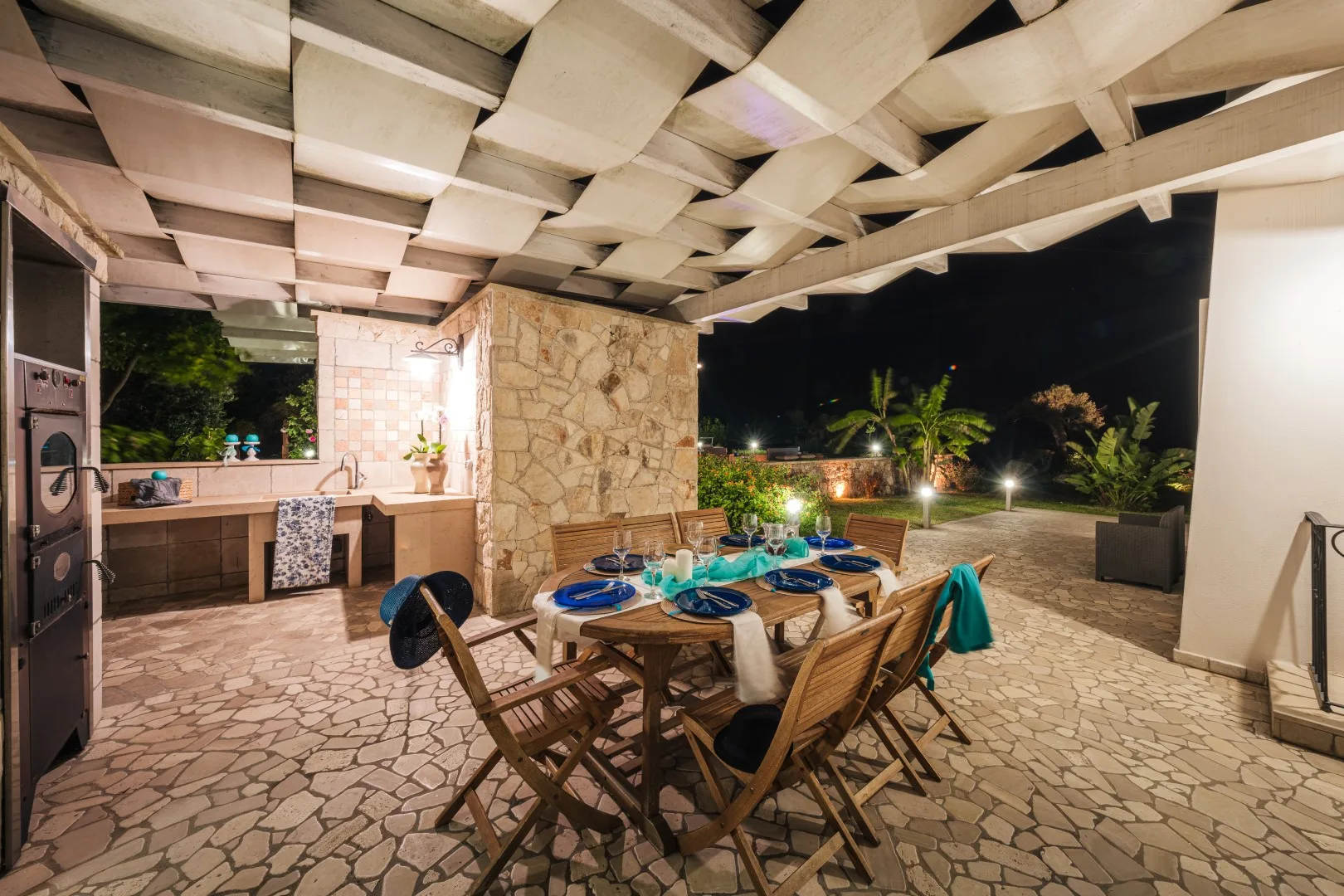 Comedor al aire libre con una mesa puesta bajo un patio cubierto.