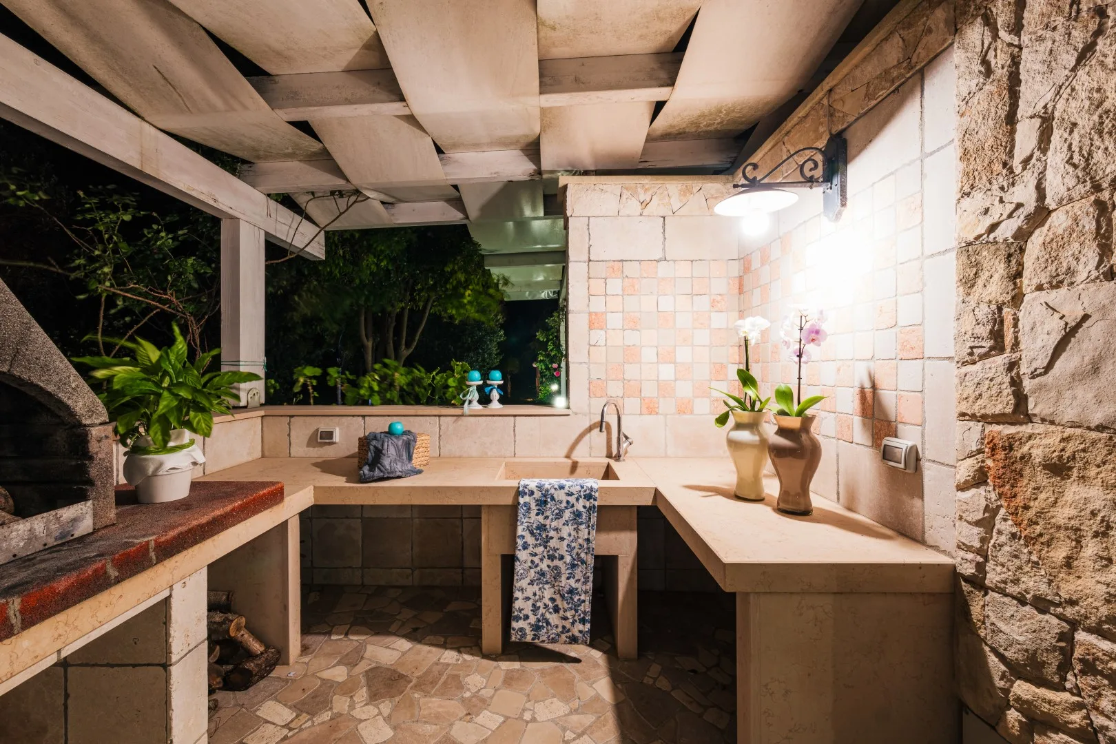 Una cocina al aire libre con encimera, fregadero y pared de azulejos.
