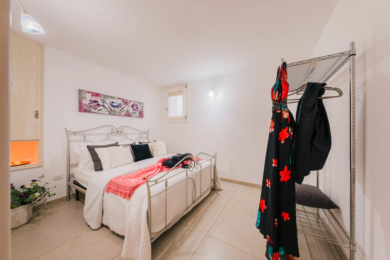 Un dormitorio luminoso con una cama y un perchero al lado.