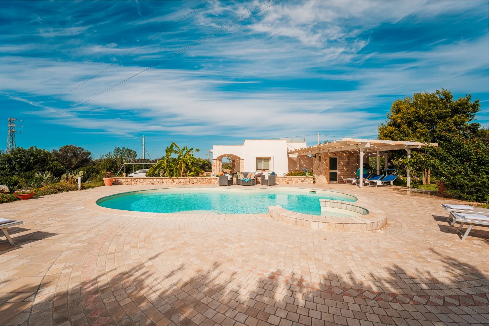Una piscina al aire libre junto a un edificio bajo y un patio pavimentado.