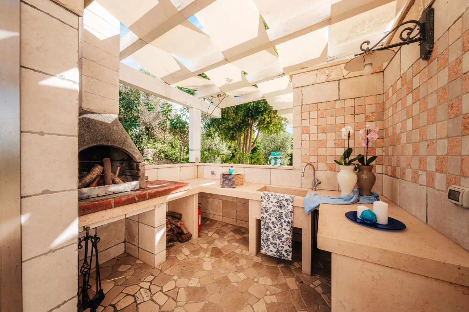 Una zona de cocina al aire libre con horno integrado y una encimera bajo una pérgola.