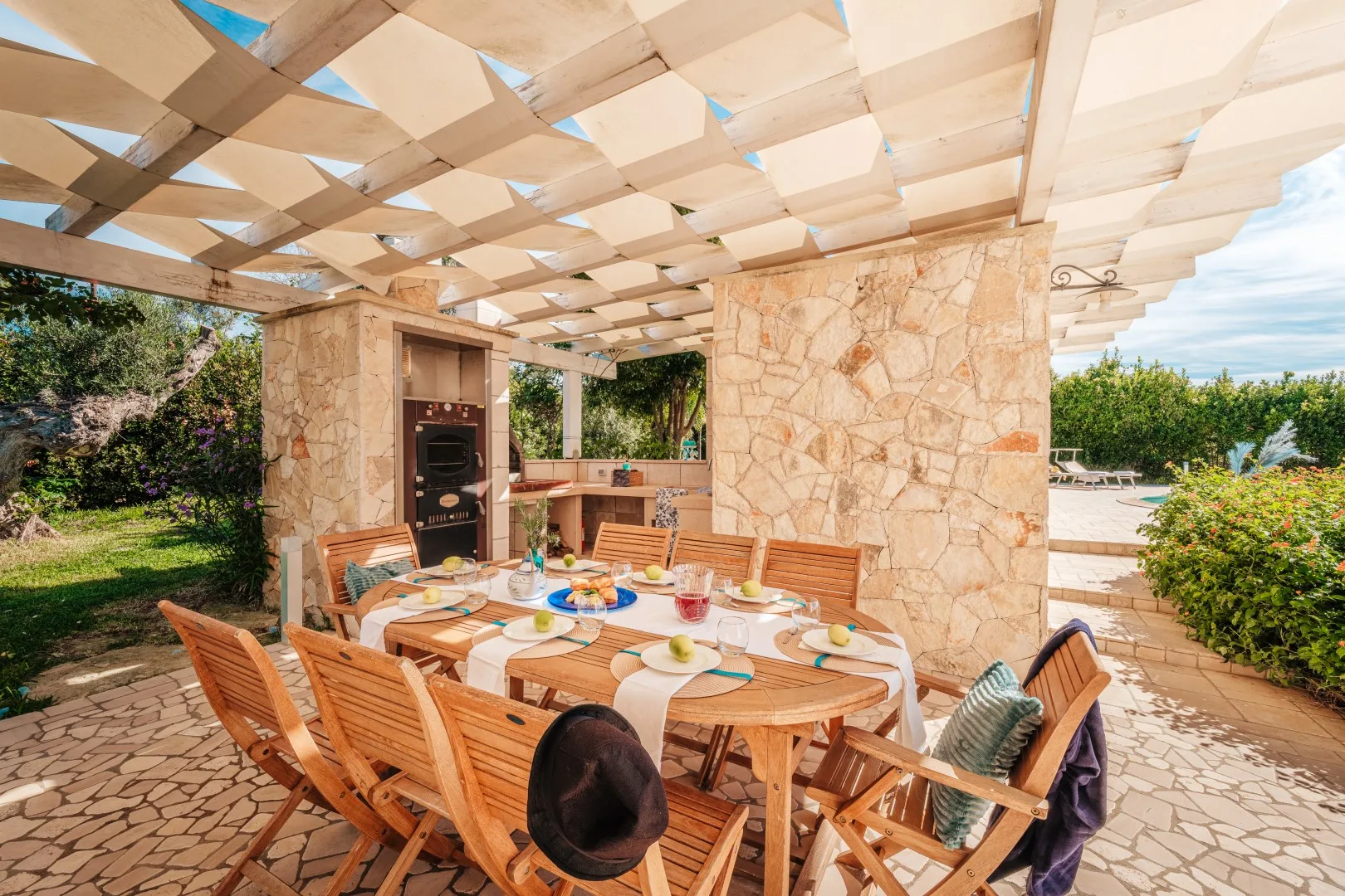 Una zona de comedor al aire libre con una mesa de madera bajo una pérgola.
