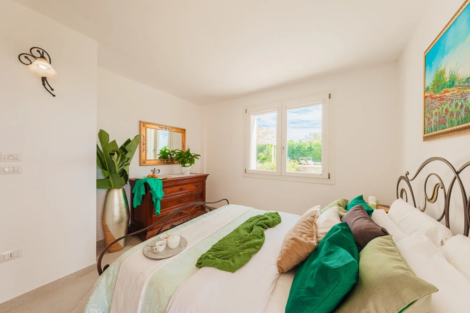Un dormitorio luminoso con una cama vestida con ropa de cama verde y blanca.