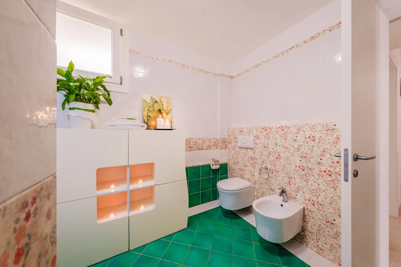 Un baño luminoso con azulejos, un inodoro y un lavabo suspendido.