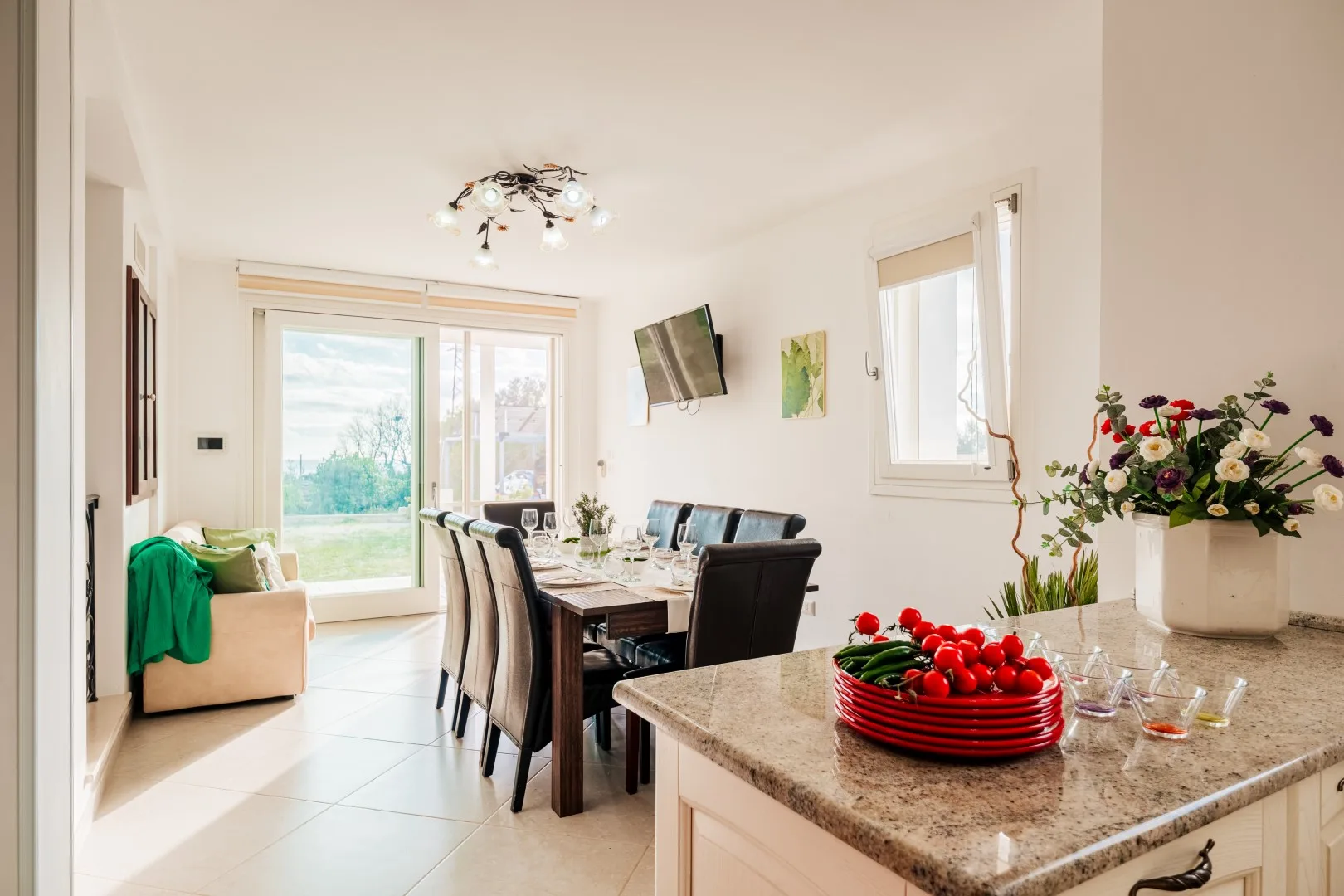 Un comedor luminoso con mesa y asientos junto a una zona de estar soleada.