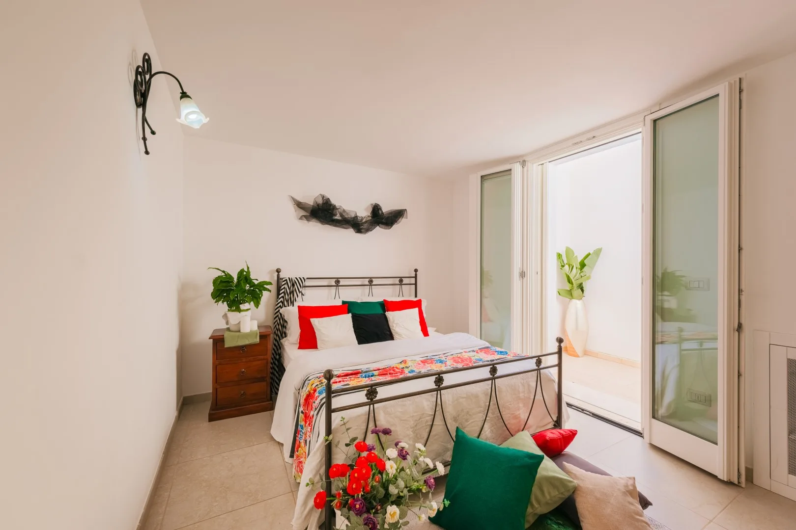 Un dormitorio luminoso con una cama junto a puertas de vidrio abiertas.