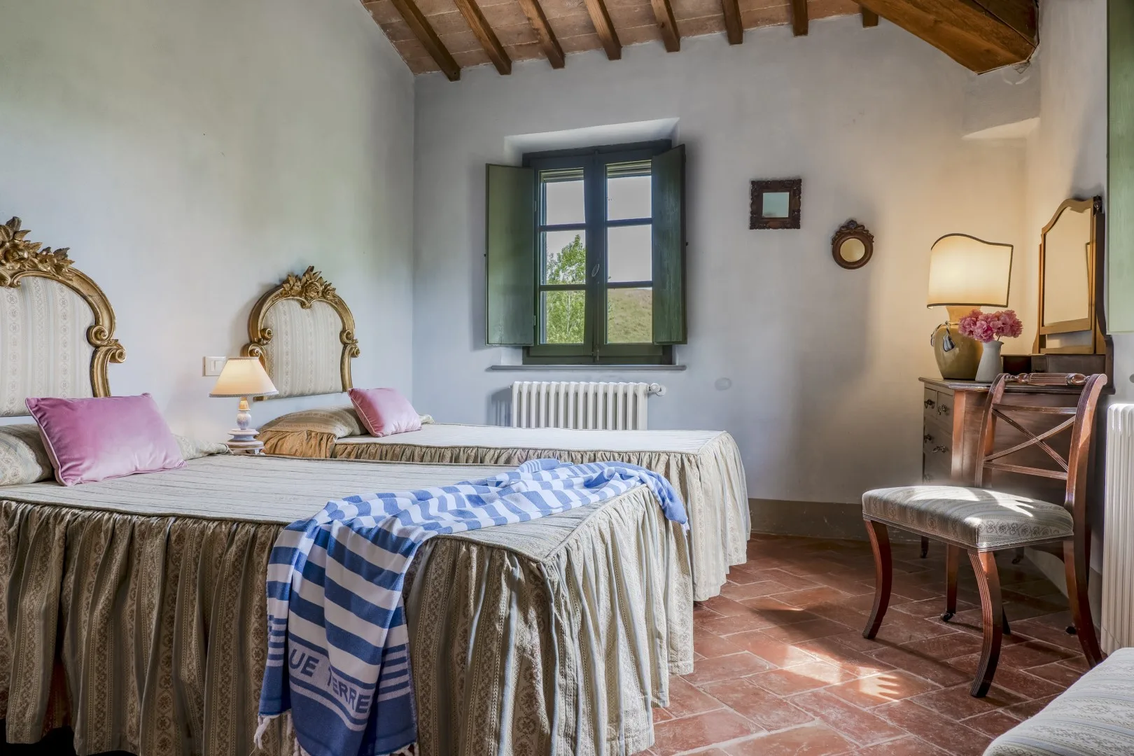 Un dormitorio con dos camas, una ventana y vigas de madera expuestas en el techo.