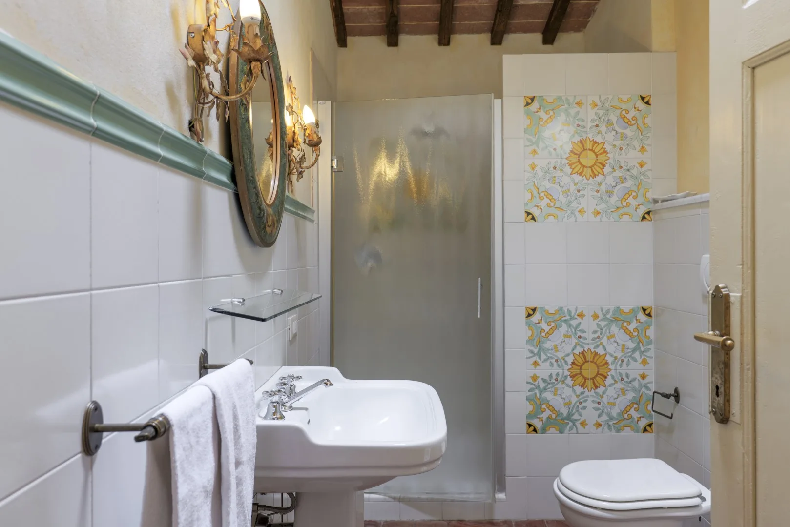 Un baño alicatado con lavabo, inodoro y paneles decorativos estampados.