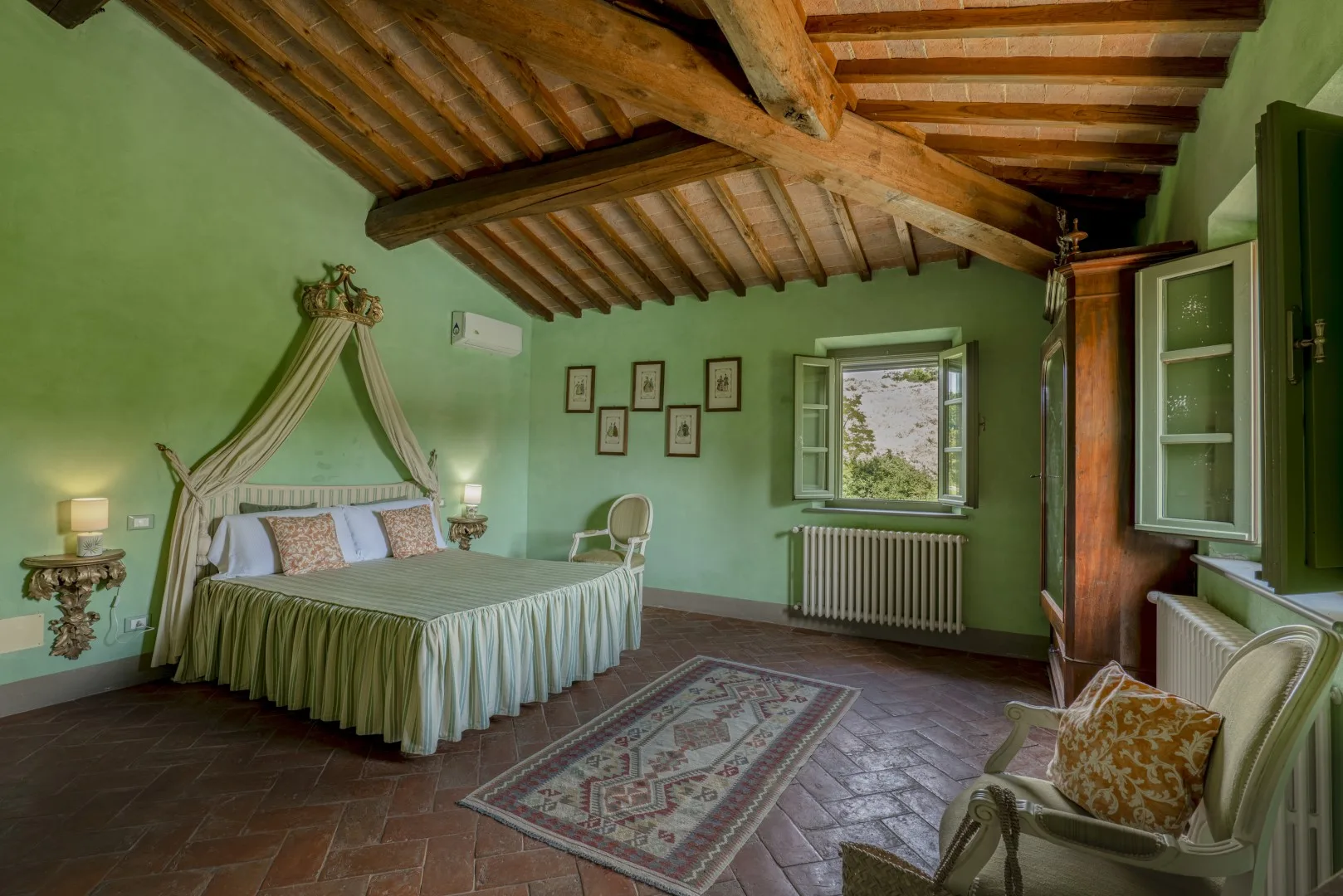 Un dormitorio con cama con dosel, paredes verdes y vigas de madera vistas en el techo.
