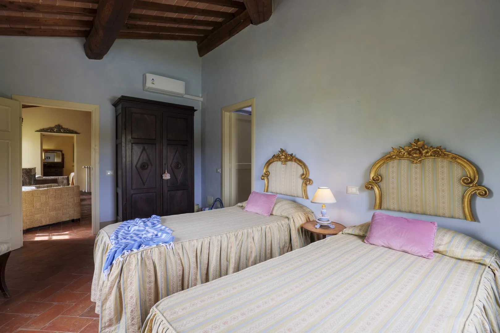 Dormitorio con dos camas, cabeceros ornamentados y vigas de madera expuestas en el techo.