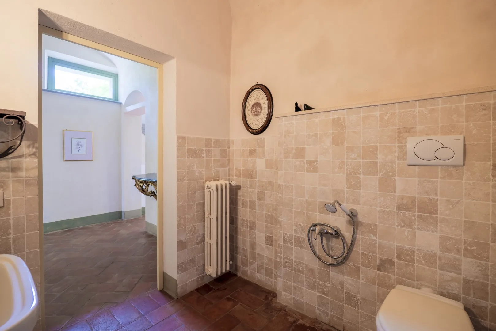 Un baño alicatado con ducha de pared y una puerta abierta.